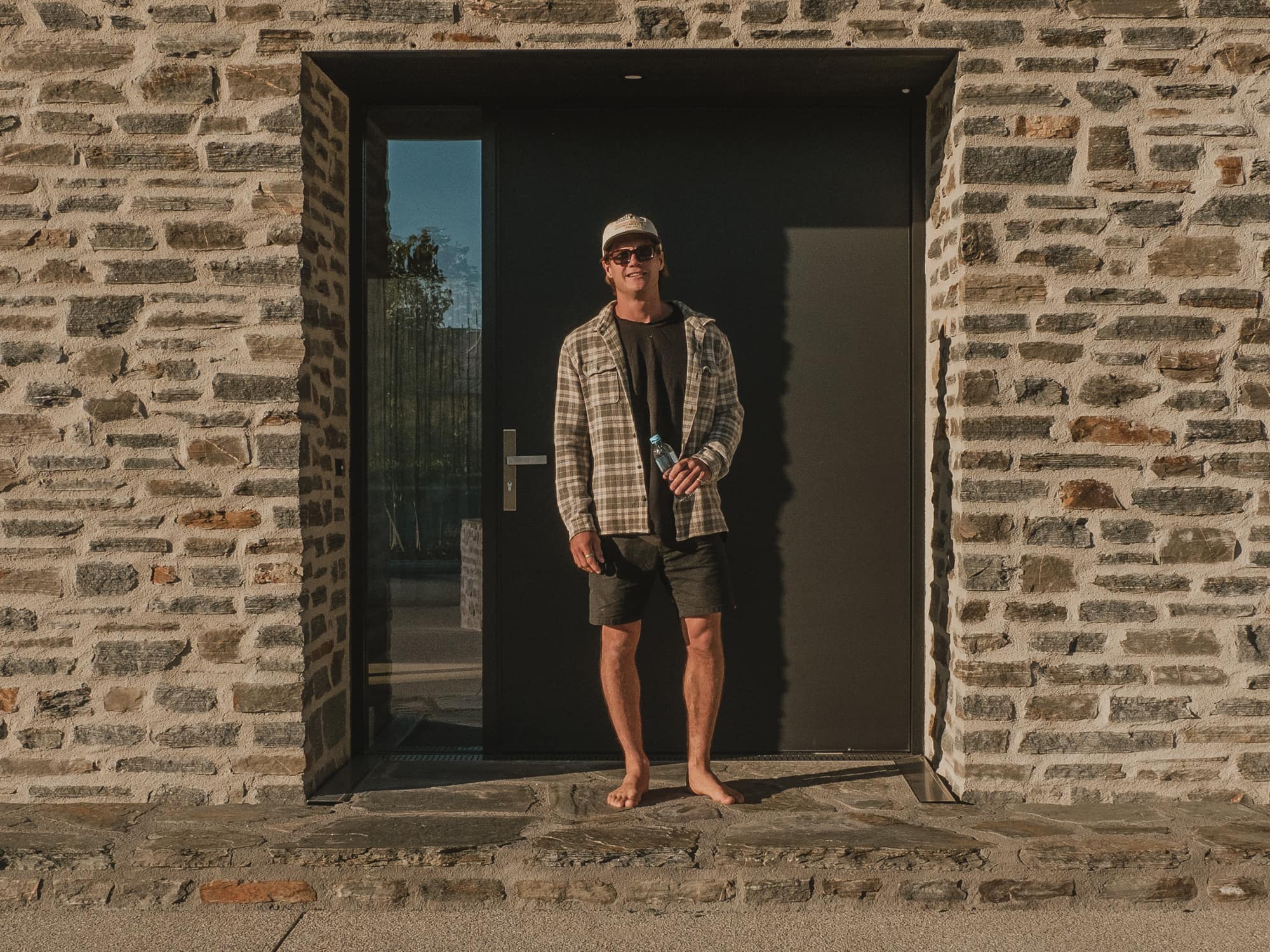 Central Otago schist entrance with a black steel door in evening light