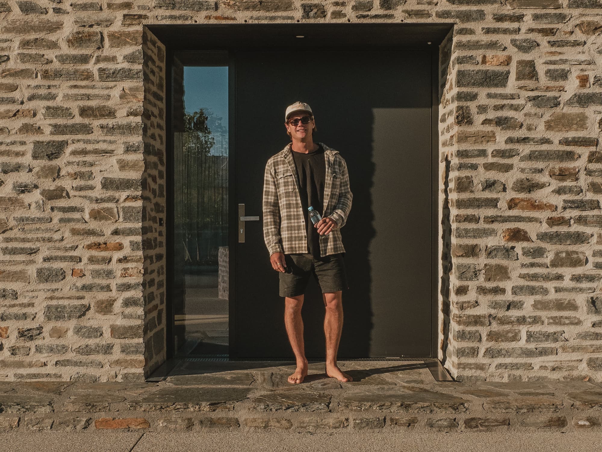 Central Otago schist wall and black steel entry door in low evening light