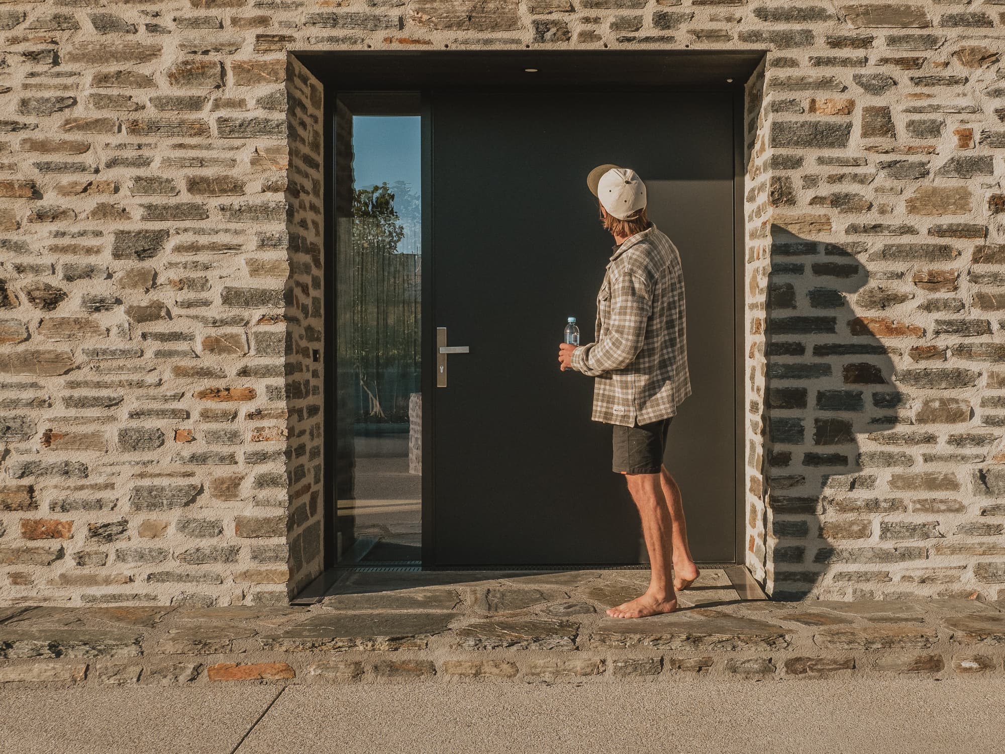 Central Otago schist wall and black steel entry door in low evening light